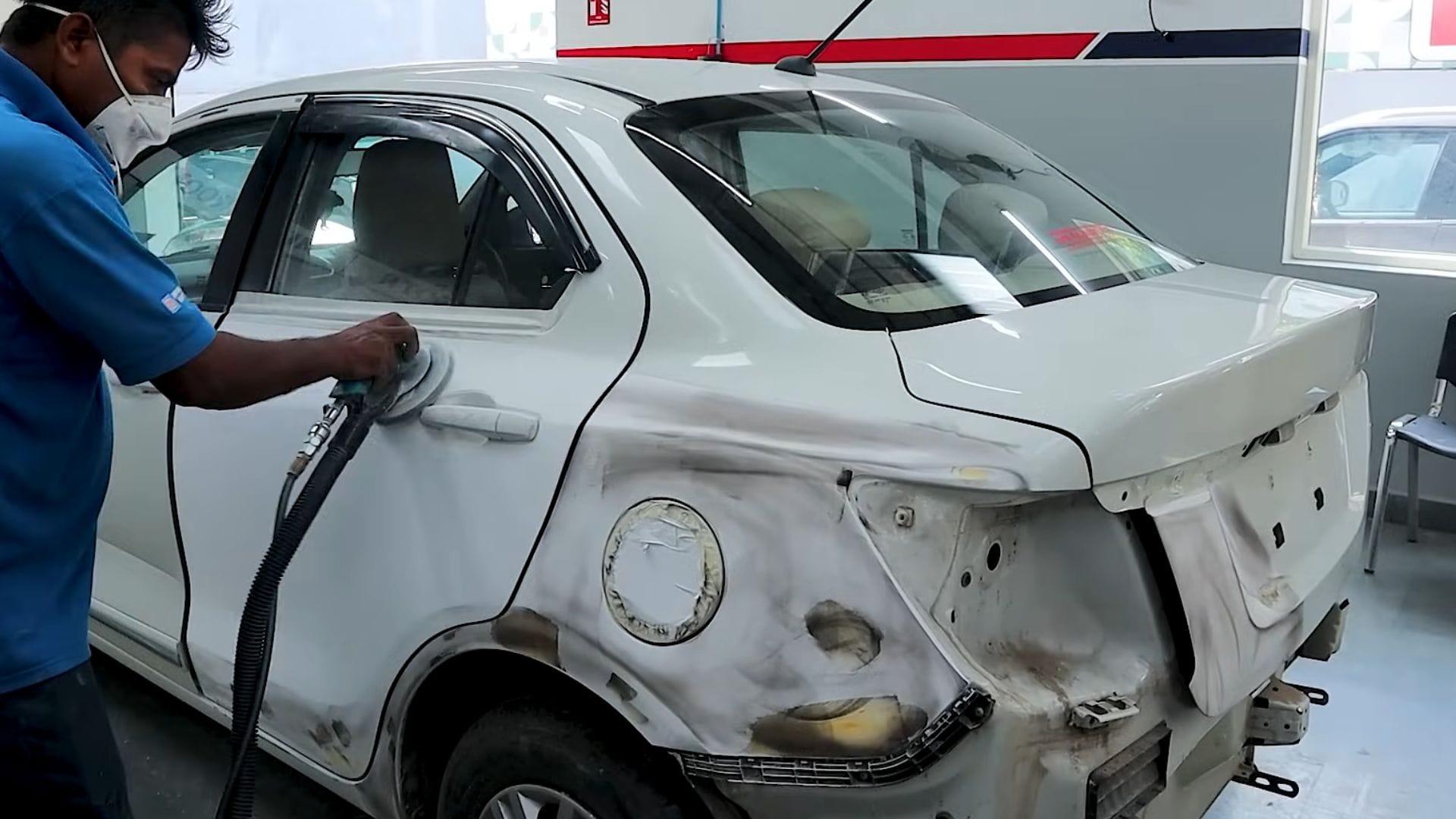 Technician preparing a car body panel for dent and paint repair