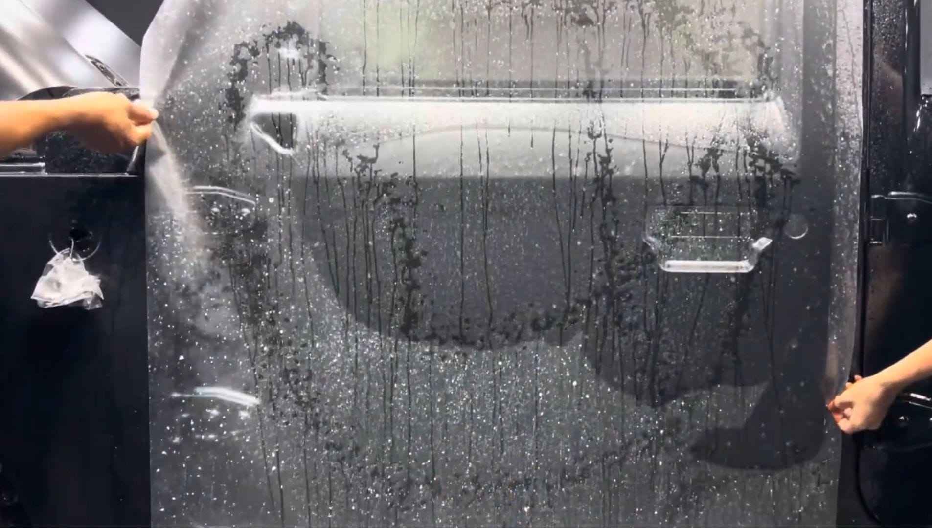 Technician installing paint protection film on a car