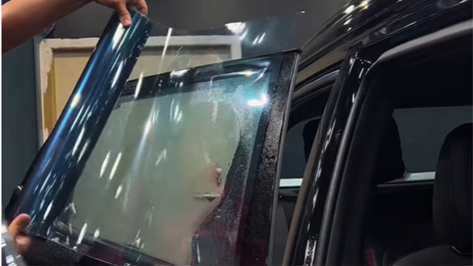 Technician installing sun film on a car window